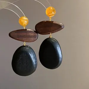 Detailed macro shot of ethnic style wooden drop earrings with amber beads and black pendants