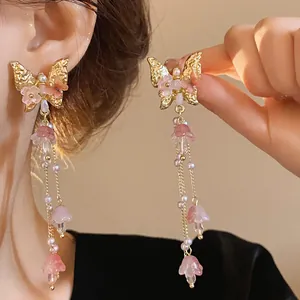 Close-up detail of elegant butterfly crystal tassel earrings with pink flower charms