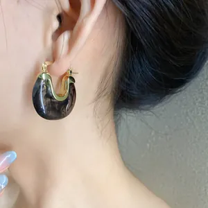 Close-up detail of U-shaped resin geometric hoop earrings with black marbled texture