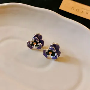 Close-up macro view of vintage purple enamel pansy flower stud earrings with crystal