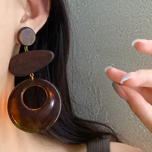 Macro view of vintage wood and amber resin hollow drop earrings on a female model