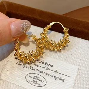 Close-up detail of 18k gold-plated textured beaded hollow hoop earrings for women