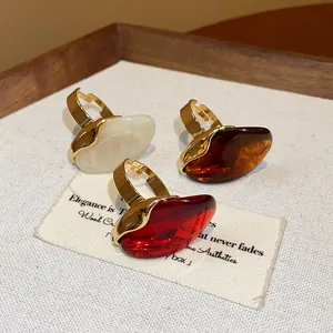 Macro view of three resin oval open rings in white, amber, and vibrant red colors