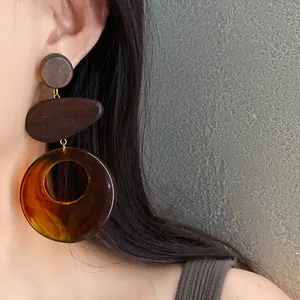 Close-up view of a model wearing stylish geometric wood and amber resin drop earrings
