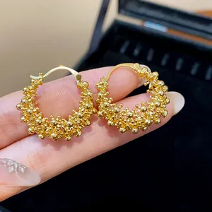 Close-up of 18k gold plated hoop earrings with textured bubbly hollow design details
