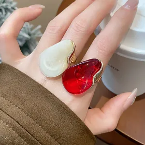Close-up detail of oversized red and white resin open rings with gold metallic base