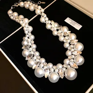 Makroansicht einer edlen Kunstperlenkette mit funkelnden Strass-Akzenten auf schwarzem Samt.
