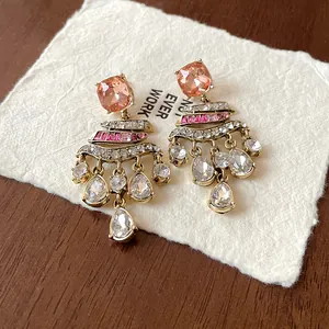 Close-up of vintage gold-tone chandelier earrings with peach and white crystals.