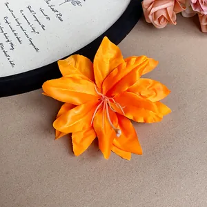 Close-up of a vibrant orange artificial lily flower hair clip in a vintage setting