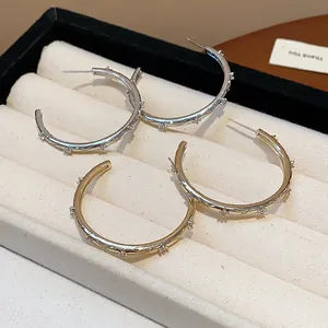 Detailed view of silver and gold hoop earrings with zircon cross pattern in a jewelry tray.