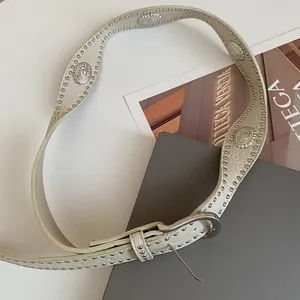 Detailed view of a stylish cream leather belt with silver studs and vintage oval conchos.