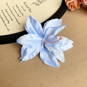Detail view of an elegant light blue artificial lily hair clip with fabric petals.
