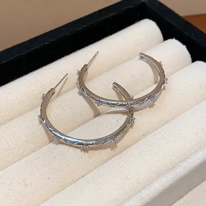 Detail view of silver-toned hoop earrings with sparkling zircon stones in a jewelry box