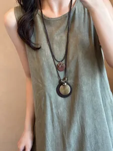 Close-up van een lange etnische halsketting in vintage-stijl met ronde hangers op een model.