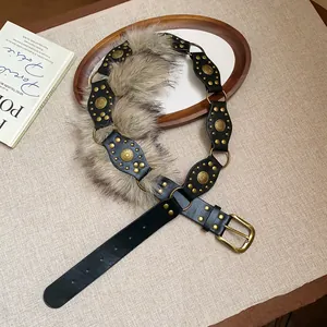 Close-up of vintage rivet leather belt with faux fur detailing on a textured background
