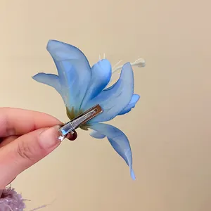 Close-up of a dreamy blue fabric lily flower hair clip with a silver metal alligator clip