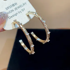 Detailed close-up view of gold criss-cross hoop earrings with sparkling cubic zircon stones