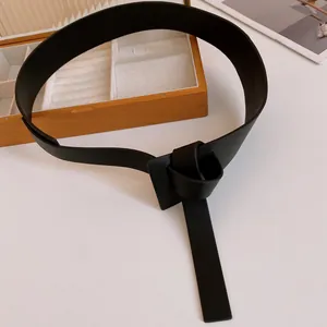 Detailed view of a stylish black leather belt featuring a unique knot-style buckle