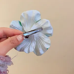Detail view showing the back metal duckbill clip of the white lily flower hairpiece.