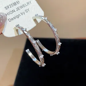 Macro detail of S925 silver needle hoop earrings with zircon crossover design