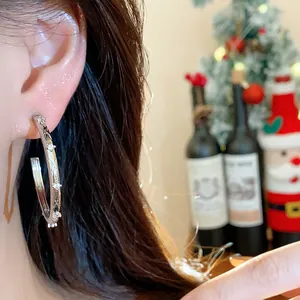 Close-up detail of stylish silver hoop earring with criss-cross zircon pattern on model
