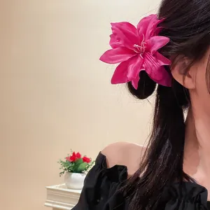 Close-up of a vibrant magenta lily flower hair clip on dark hair for a retro look.