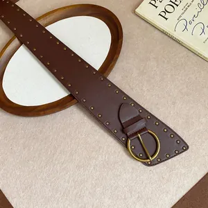 Detail of a wide brown leather belt with gold rivets and a round vintage buckle.