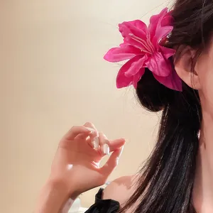 Detailed close-up of a pink fabric lily flower hair clip worn on dark hair