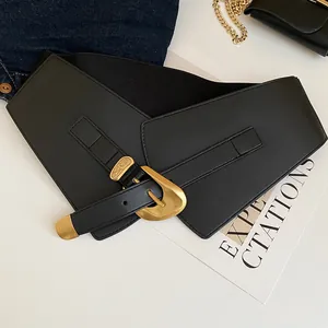 Close-up of a wide black elastic waist belt with a vintage gold buckle detail.