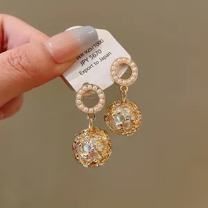 Detailed shot of vintage gold earrings with pearl circle and textured sphere drop