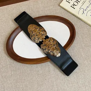 Detail of black elastic belt featuring intricate gold filigree butterfly buckle