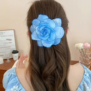 Große blaue Organza-Blumen-Haarspange getragen auf langem braunem Haar im Zimmer
