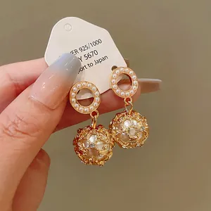 Close-up of vintage gold hollow sphere earrings with pearls and 925 silver needles.