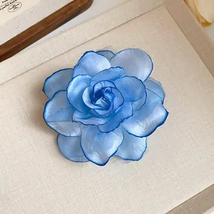 Nahaufnahme einer blauen Stoffblume mit geschichteten Blütenblättern und Marine-Rand