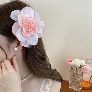 Eleganter übergroßer Stoffblumen-Haarclip an Model mit Perlen-Schmuckaccessoires
