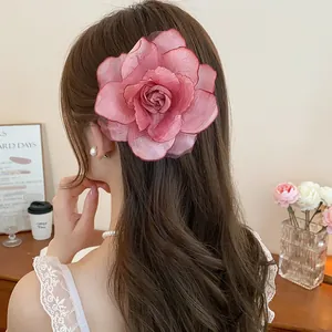 Elegante Rückansicht einer großen rosa Organza-Rosen-Haarklammer auf braunem Haar