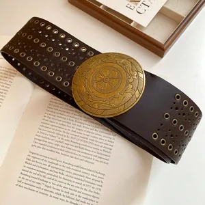 Detail view of a vintage brown leather belt with bronze eyelets and ornate buckle