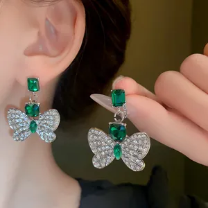 Elegant detail view of emerald green butterfly earrings with sparkly silver rhinestones