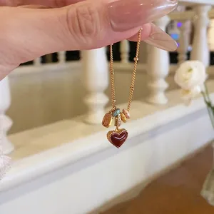Close-up view of a gold-plated heart necklace featuring enamel charms and sparkling zircon