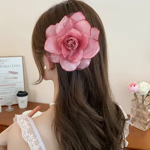Große rosa Stoff-Rosen-Haarklammer an langem braunem gewelltem Haar im Detail