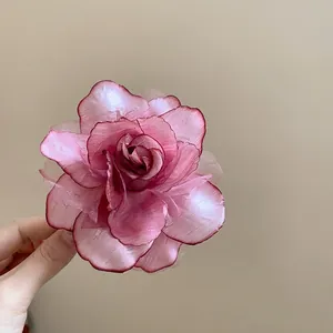 Detailansicht eines handgefertigten rosa Organza-Rosenblüten-Accessoires in der Hand