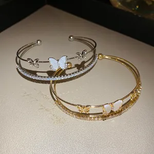 Vista de detalle de brazaletes de oro y plata con elegantes mariposas de circón