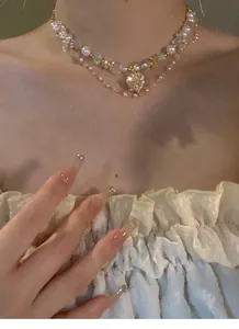 Elegante Halskette im Palast-Stil mit Perlen und funkelndem Herzanhänger am Model.