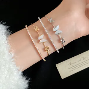 Primer plano de elegantes brazaletes de mariposa con circonitas y pulseras tenis de cristal