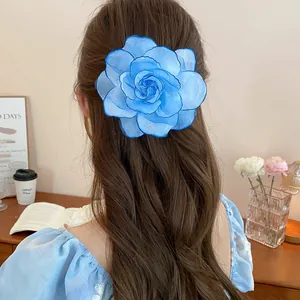 Detailansicht einer großen blauen Stoffblumen-Haarklammer auf langem braunem Haar.
