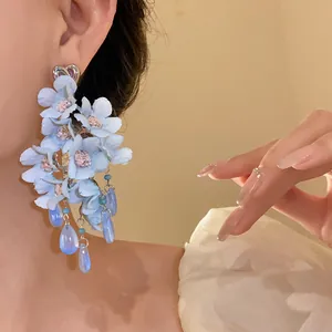 Primo piano di orecchini a fiore blu con nappe in vetro e perno a cuore argentato
