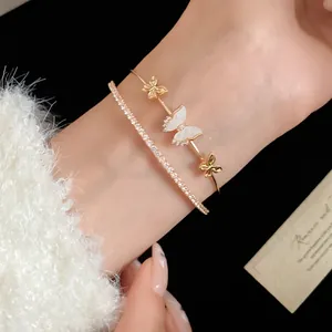 Detalle de una elegante pulsera de oro de dos capas con circonitas y dijes de mariposas blancas