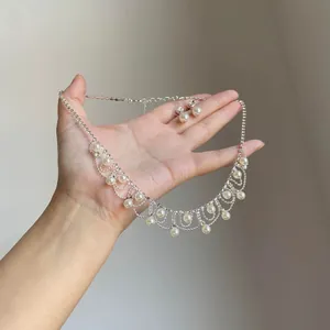 Detail of elegant vintage rhinestone pearl fringe necklace and earrings held in hand.