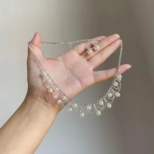 Detail view of vintage pearl lace fringe necklace and stud earrings set held by hand
