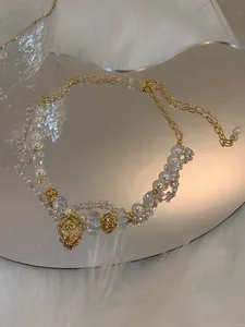 Detailansicht einer luxuriösen Goldkette mit Perlen, Kristallen und Herzanhänger.